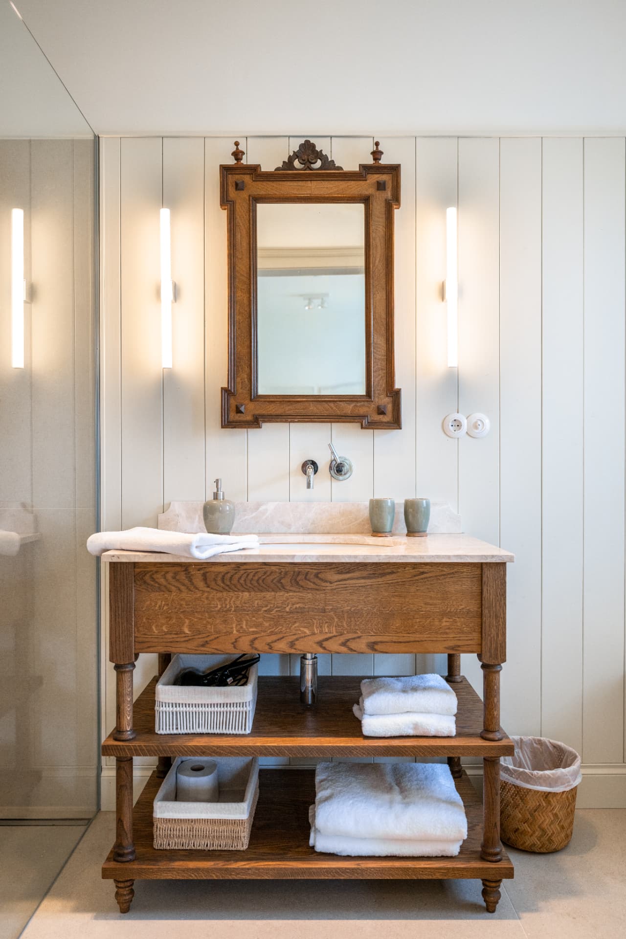 Badezimmer mit antikem Waschtisch, Holzwand und Spiegel